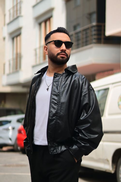 Free Confident man with sunglasses and leather jacket in urban street setting, showcasing modern style. Stock Photo