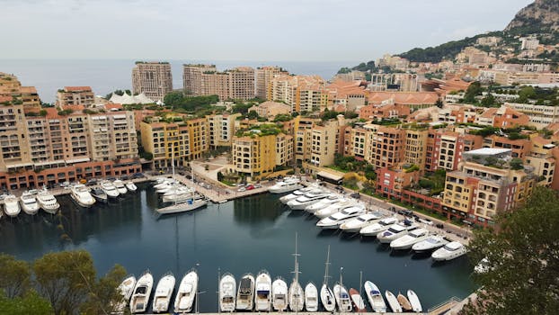 High-angle view of Monaco's marina featuring luxury yachts and colorful buildings against the seaside.