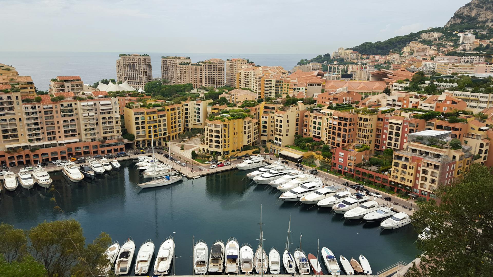 High-angle view of Monaco's marina featuring luxury yachts and colorful buildings against the seaside.