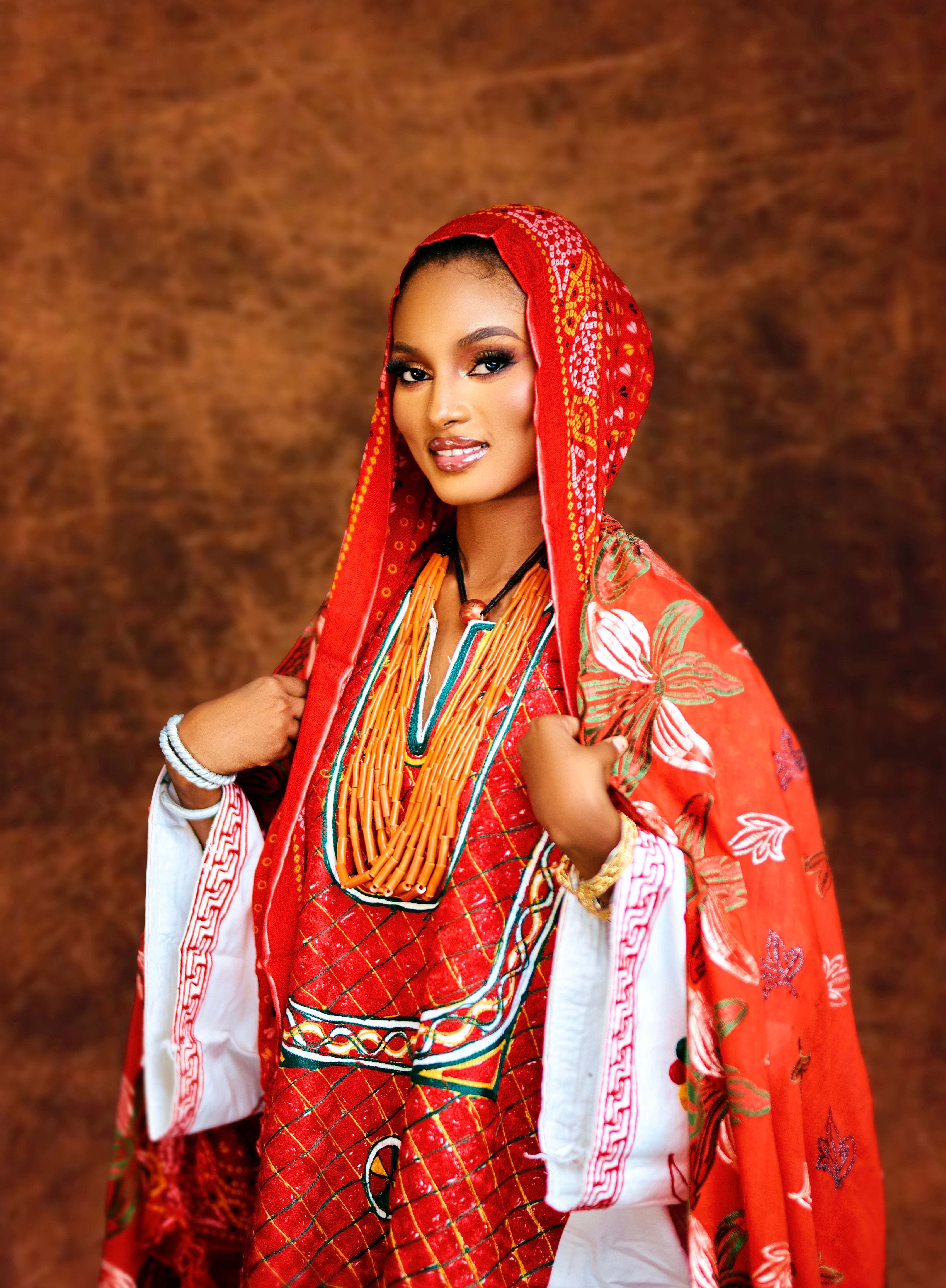 A beautiful woman in red traditional attire with intricate patterns and accessories.