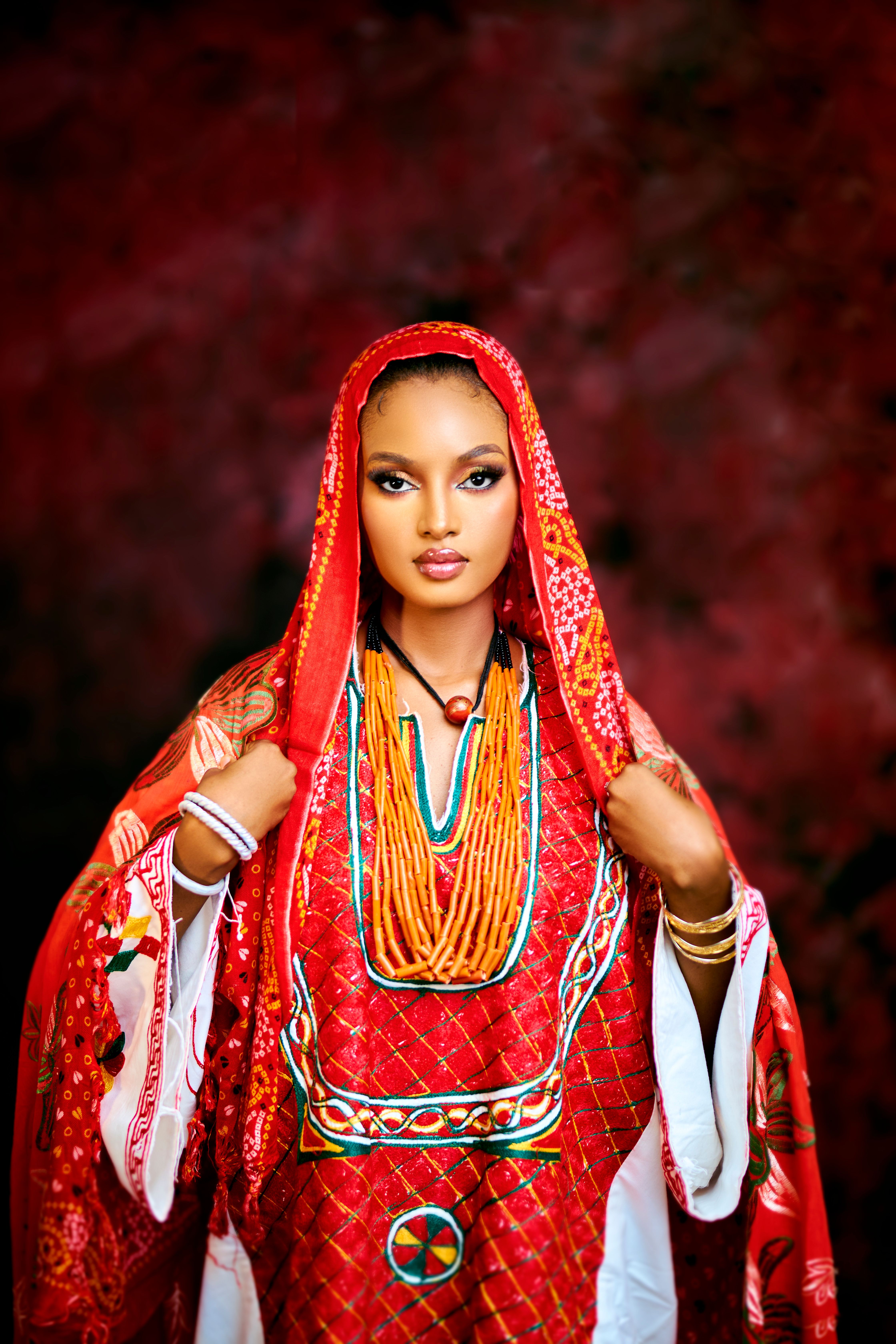 A woman adorned in vibrant red traditional African clothing with intricate details.