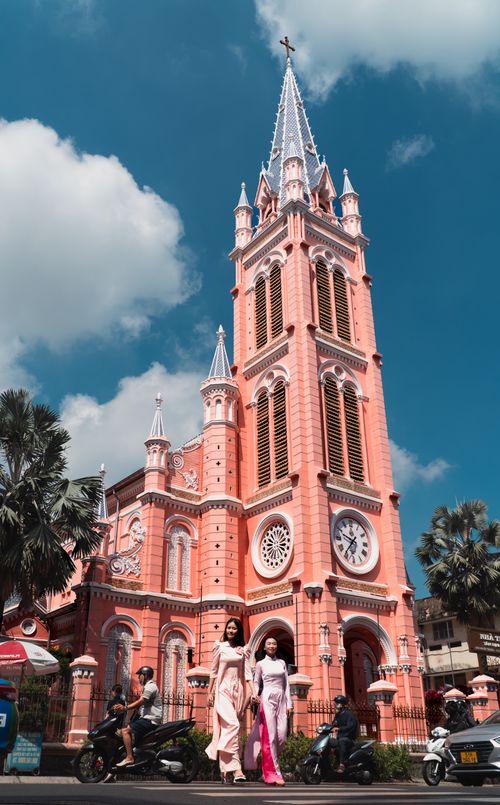 Free Stunning pink Gothic architecture with ao dai fashion in vibrant Ho Chi Minh City. Stock Photo