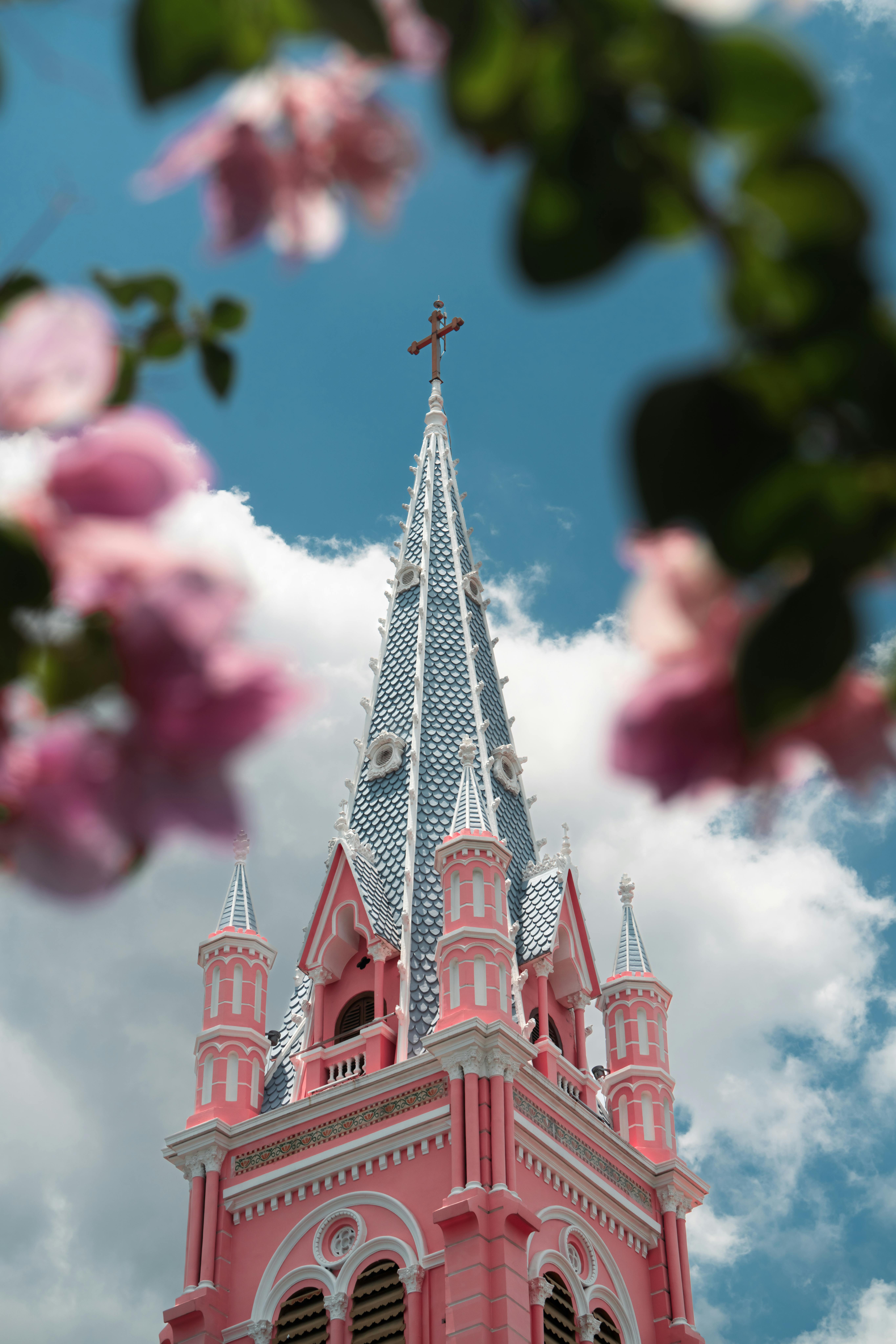 The picturesque pink facade of Tan Dinh Church surrounded by flowers under a clear blue sky in Ho Chi Minh City.