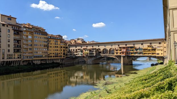 View of Ponte Vecchio and reflections on the Arno River in Florence, Italy.