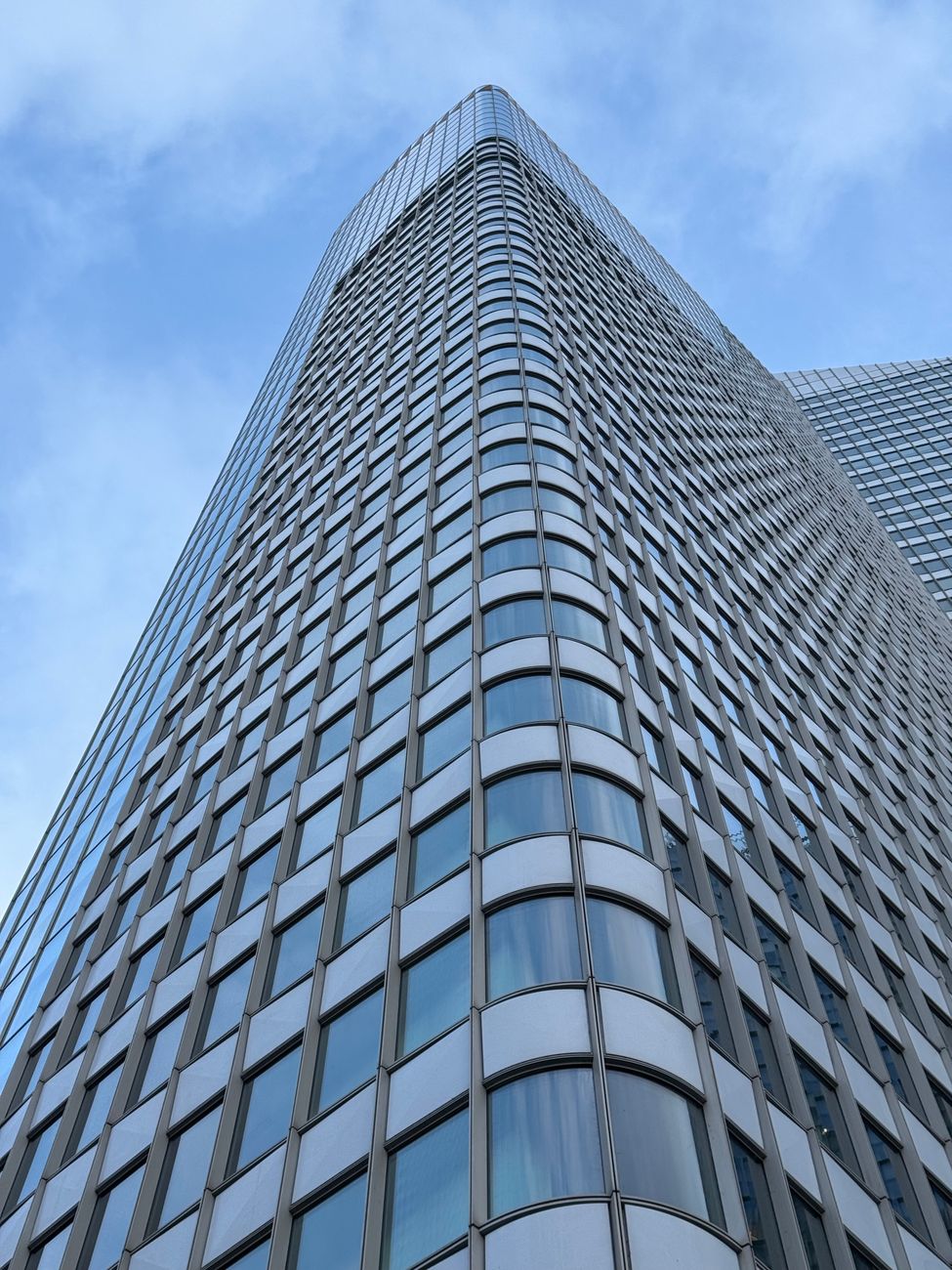 Upward view of a sleek, modern skyscraper in Paris with a blue sky backdrop.