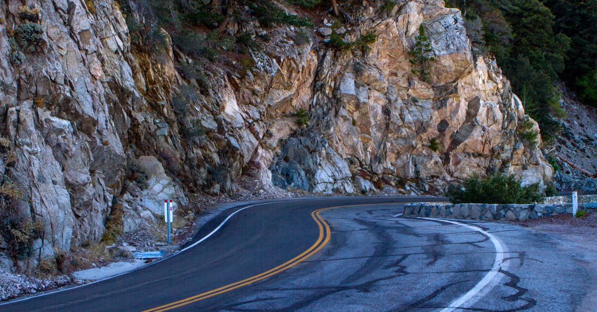 Curving mountain road on Mount Wilson, California, flanked by rocky cliffs and forest.