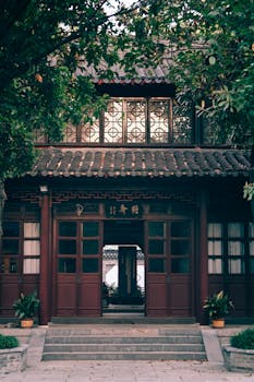 Elegant traditional Chinese building with intricate woodwork, surrounded by lush greenery in a serene setting.