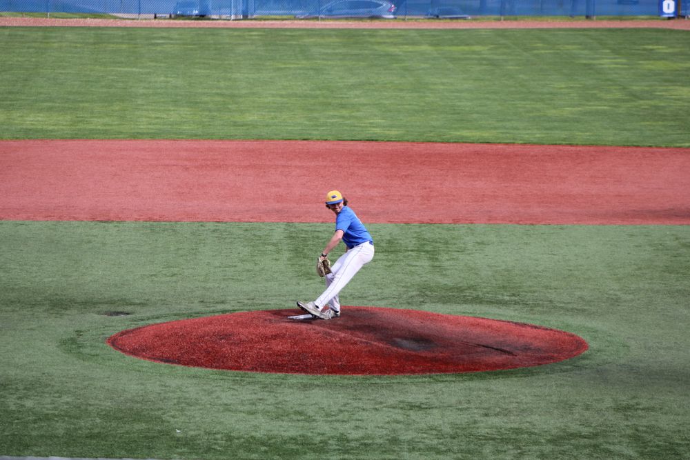 teen pitcher delivering from the mound on a sunny day
