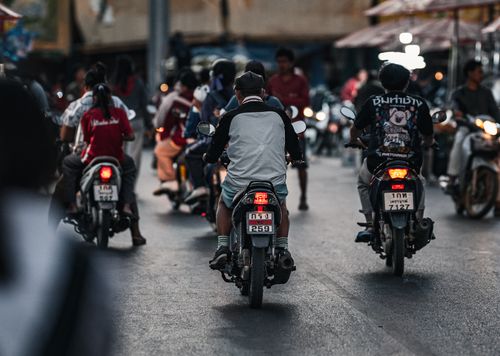 Free Busy street scene in Thailand featuring multiple people on motorbikes during the day. Stock Photo
