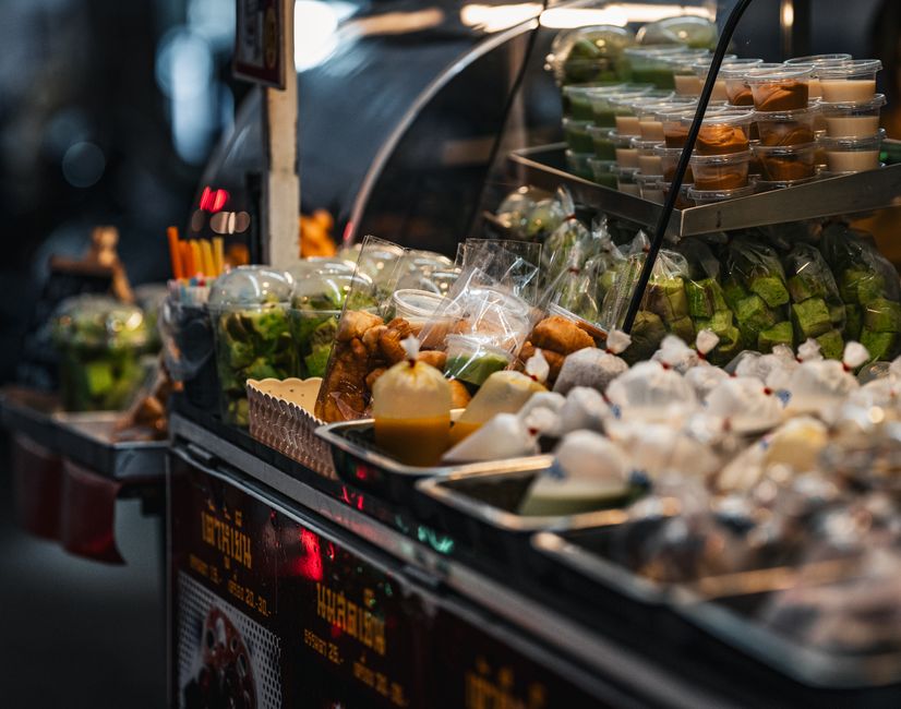 Vibrant Thai street food stall showcasing an array of traditional snacks and desserts.