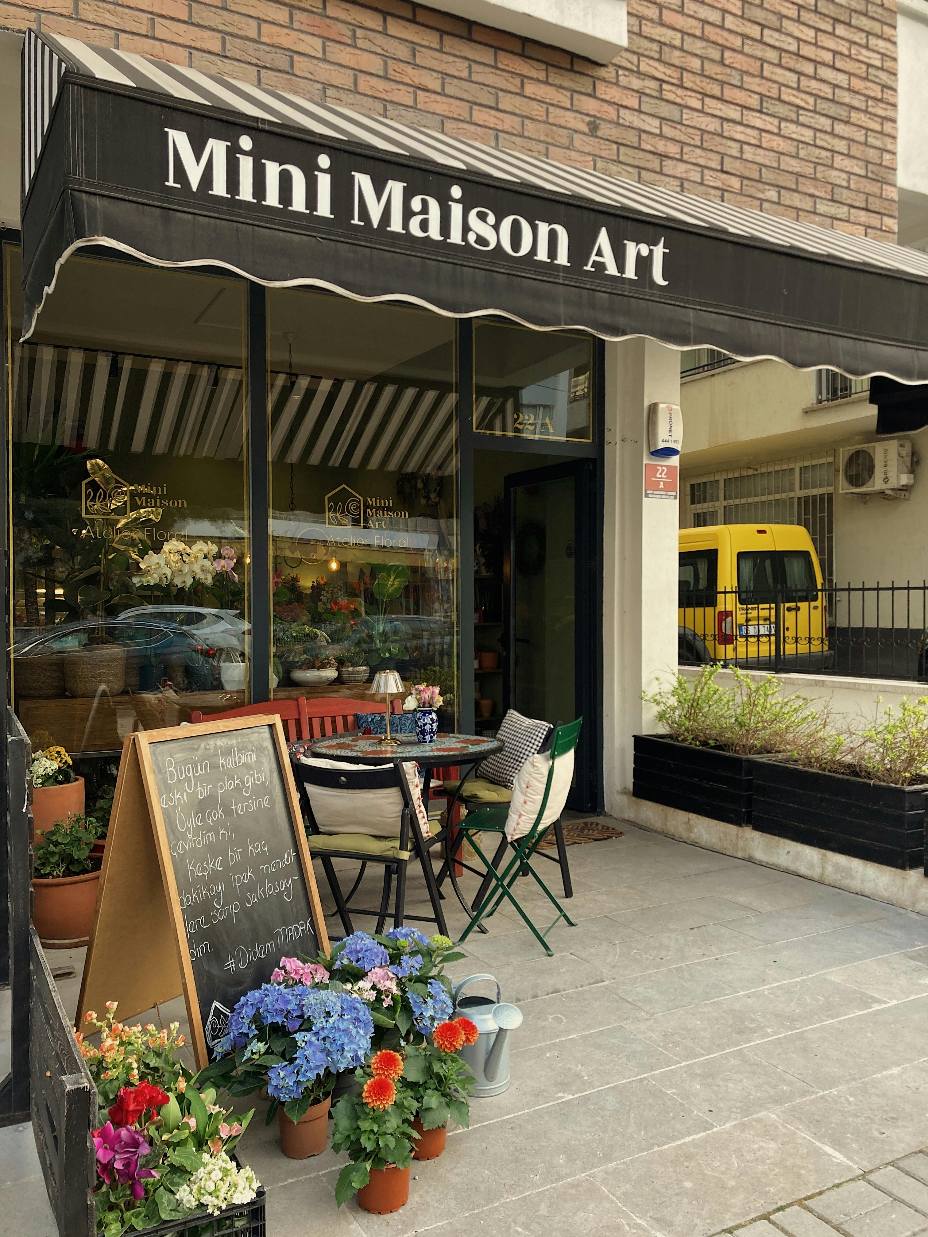 Explore the inviting outdoor patio of Mini Maison Art, adorned with colorful flowers and cozy seating.