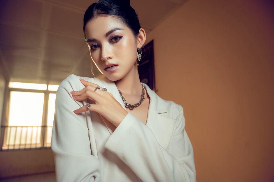 Stylish woman in white attire posing elegantly indoors with soft natural light.