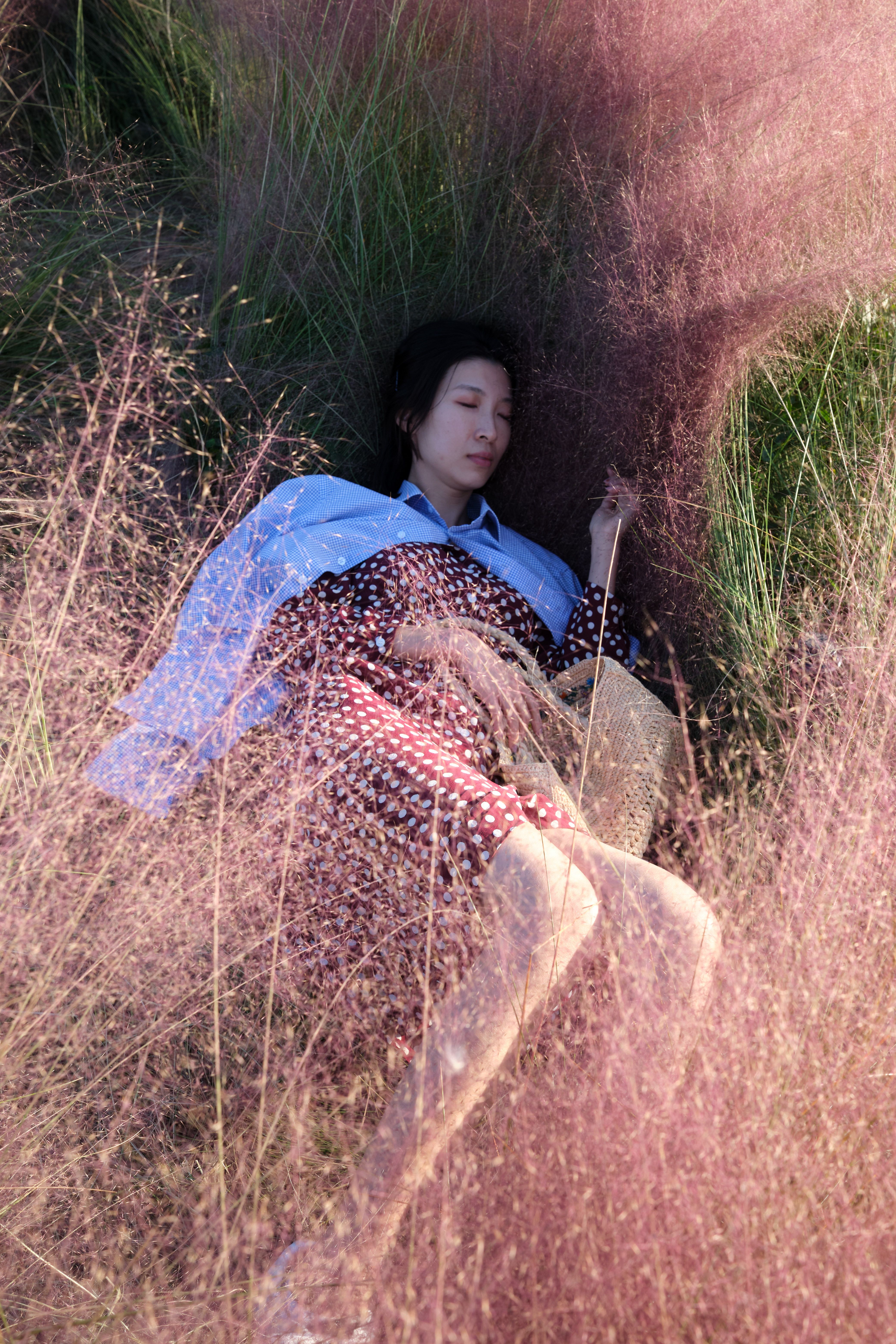 A woman peacefully lying on pastel grass surrounded by nature.