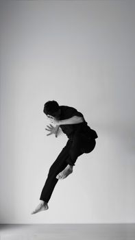 Monochrome photo of a man leaping gracefully in mid-air, showcasing motion and art.