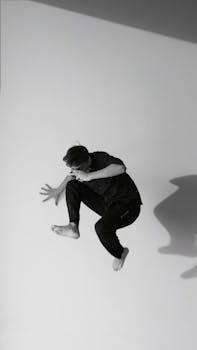 Black and white image of a male dancer leaping gracefully in mid-air.