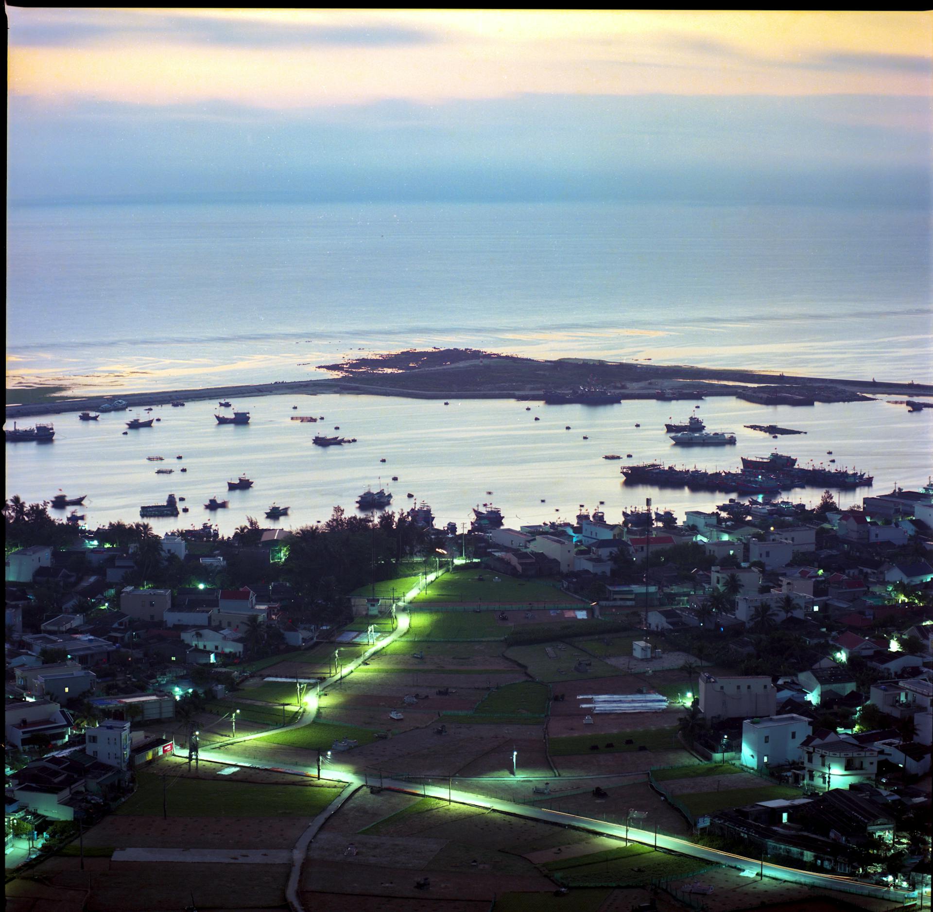 Serene aerial view of Quang Ngai coastline and boat-filled harbor at twilight, Vietnam.