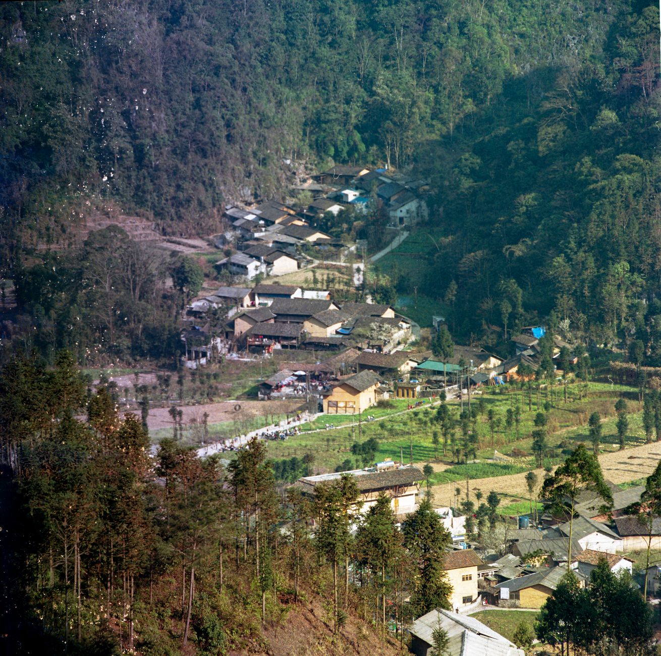 Aerial view of a picturesque village in Hà Giang, Vietnam, surrounded by lush greenery and mountains.