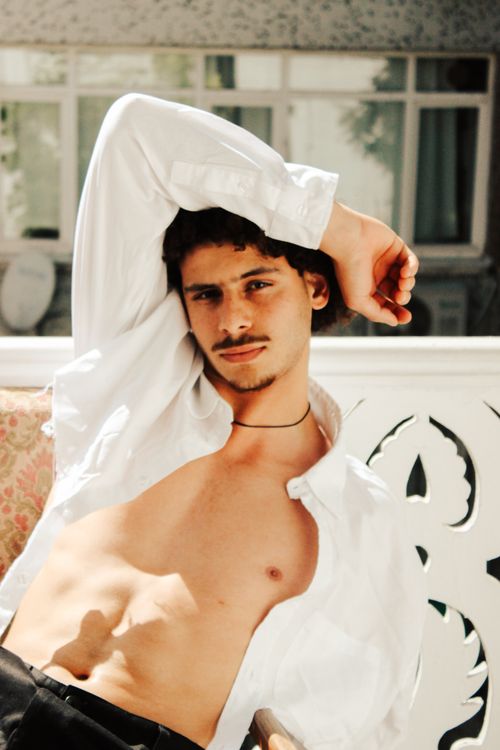 Free Shirtless young man posing outdoors in the sunshine, wearing an open white shirt. Stock Photo