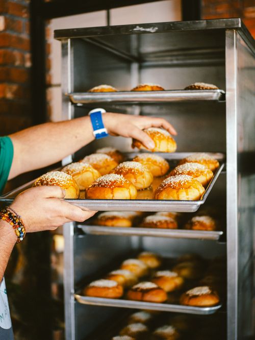 Free A baker organizing freshly baked bread rolls in an industrial kitchen setting. Stock Photo