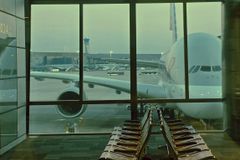 A large airplane is parked outside an airport terminal window at dawn.