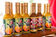 Colorful assortment of Trinidadian mango and tamarind hot sauces in bottles.