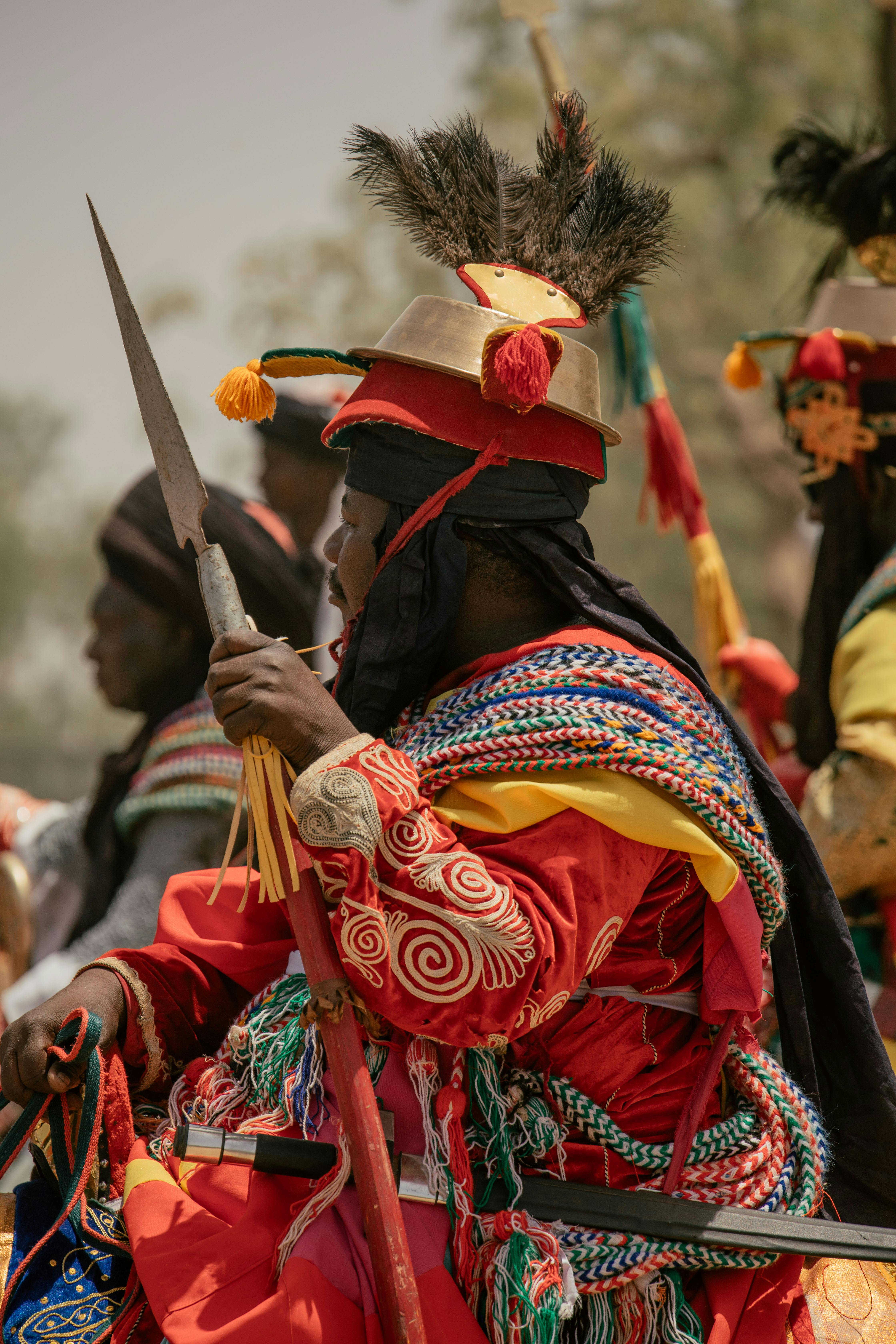 Vibrantly dressed people in traditional African costumes with detailed embroidery and accessories at a cultural festival.
