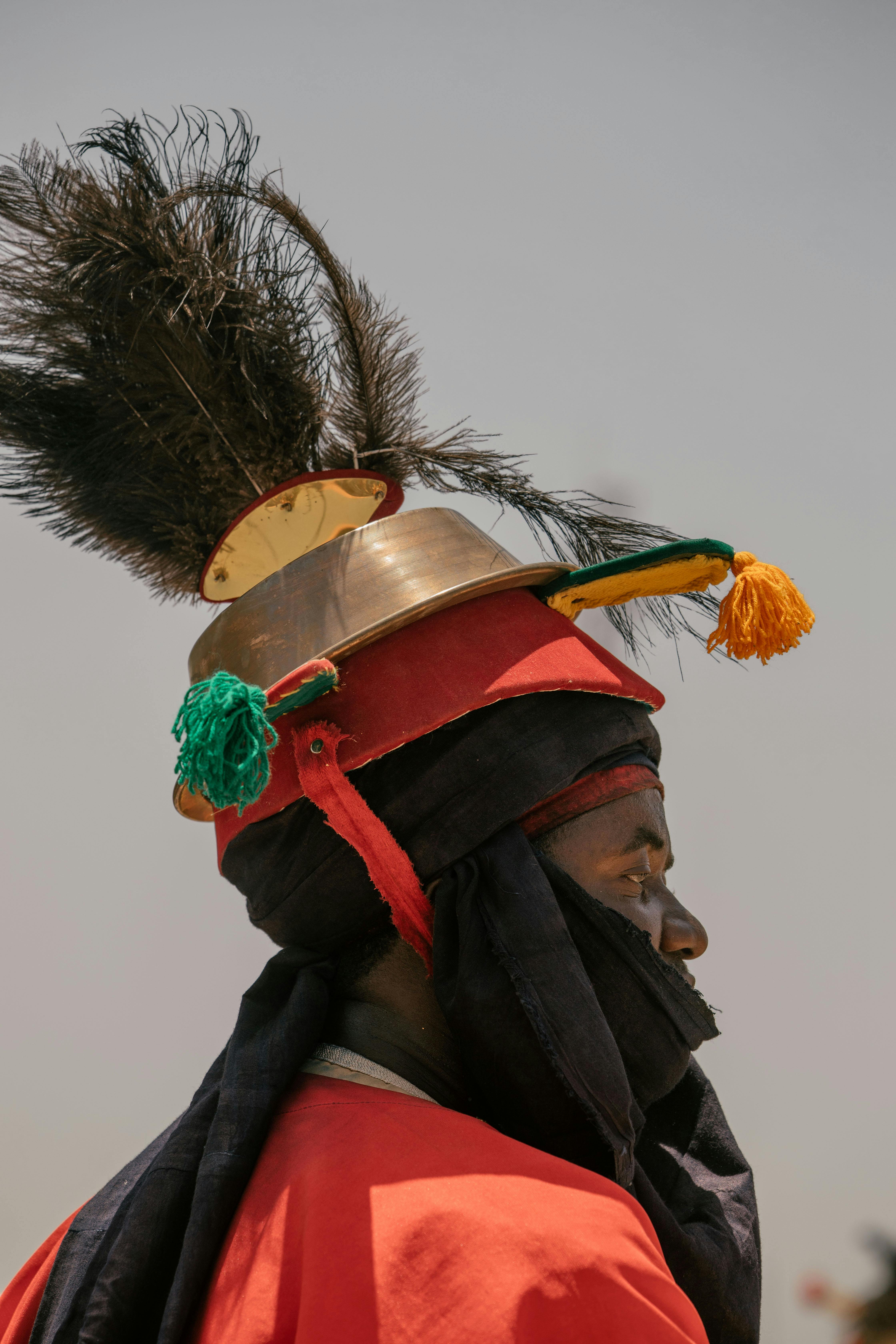 Profile of a traditional African warrior in colorful, adorned attire and cultural headwear.