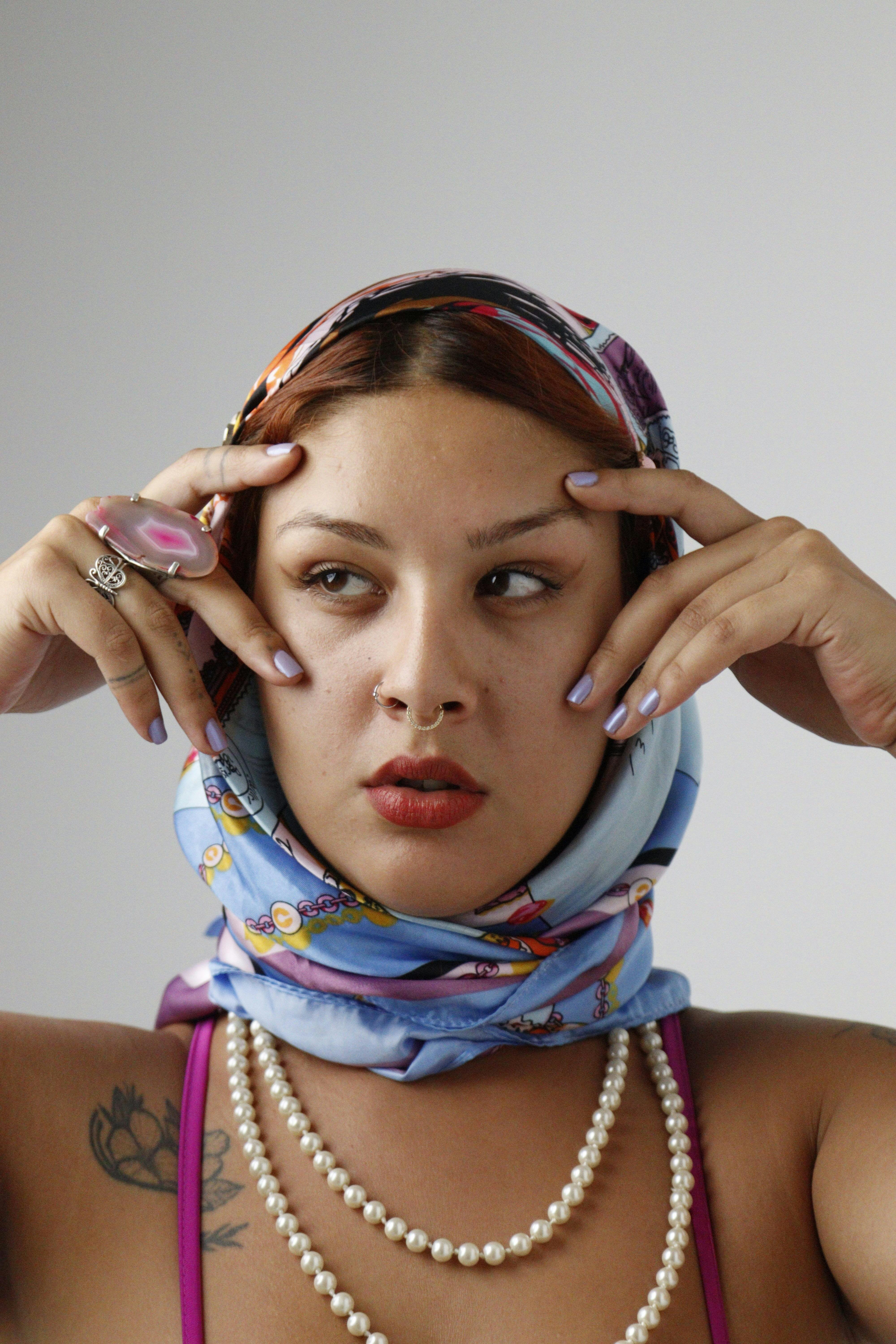 bezplatná Portrét ženy nosící barevný šátek, šperky a make-up, předvádějící moderní styl. Základová fotografie