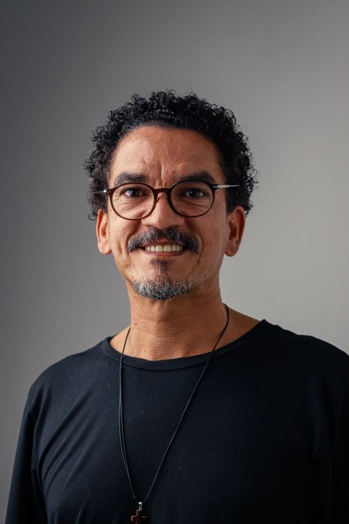 Free Portrait of a smiling man with curly hair and glasses against a neutral background. Stock Photo