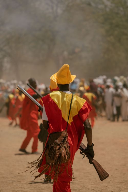 Free A colorful parade participant in traditional attire holding a rifle during a cultural festival. Stock Photo