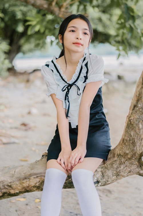 Woman Sits on Wood Branch