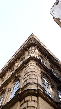 Upward corner view of a classic European building facade with ornate architecture.