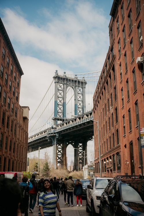Free Manhattan Bridge framed by red brick buildings in DUMBO, Brooklyn, NYC, a popular tourist spot. Stock Photo