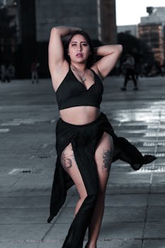 A woman poses expressively in a city plaza in Mexico City with modern architecture.