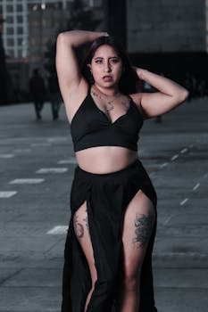Woman in black crop top and skirt with tattoos posing confidently in an urban setting in Mexico City.