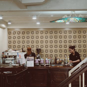 A warm and inviting coffee shop interior with baristas preparing drinks behind a stylish counter.
