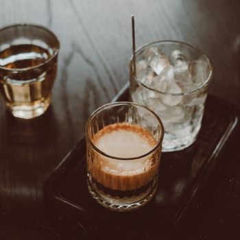 Close-up of espresso, iced water, and whiskey on a wooden table for a warm, inviting vibe.