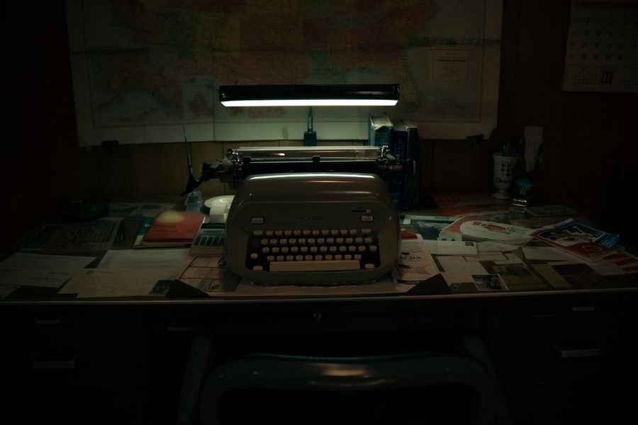 A classic office scene with a vintage typewriter on a cluttered desk under soft lighting.