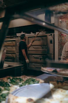 Capture of a pizza chef working in a classic New York City pizzeria, showcasing authentic pizza preparation.