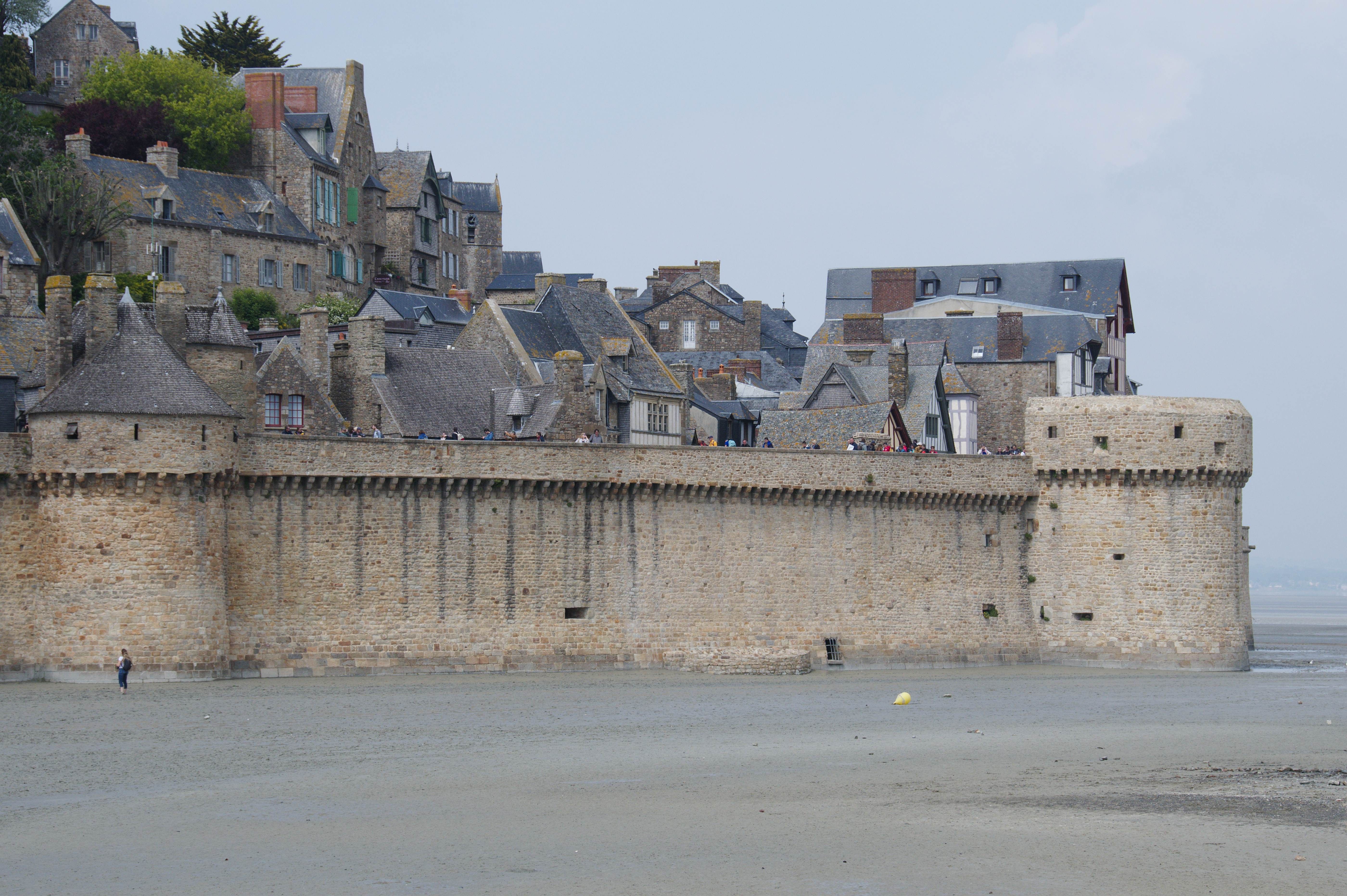 Stone fortress walls of Saint-Malo on a cloudy day, showcasing medieval architecture.