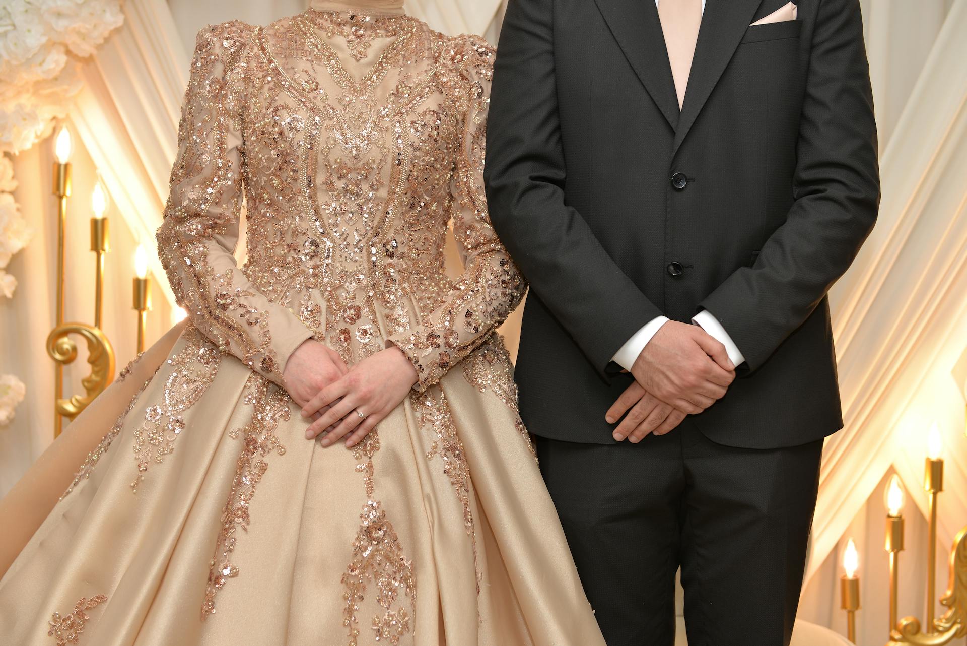 A close-up of a couple in elegant wedding attire featuring a shimmering ornate gown and a classic suit.