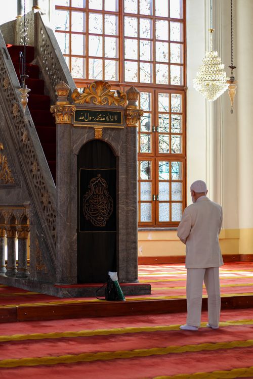 Free A man prays inside a beautifully decorated mosque bathed in natural sunlight. Stock Photo