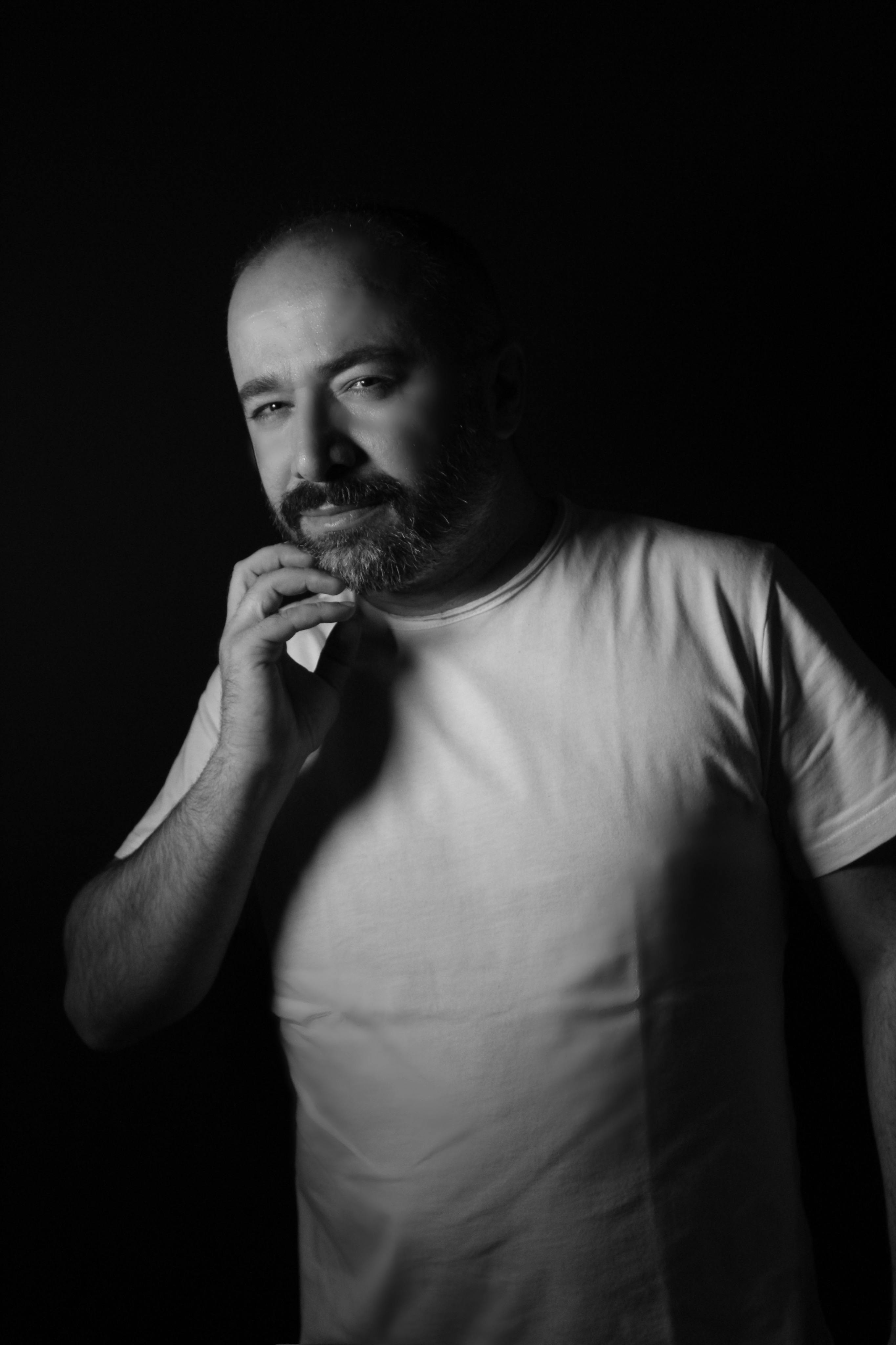 Dramatic black and white portrait of a thoughtful man in studio lighting.