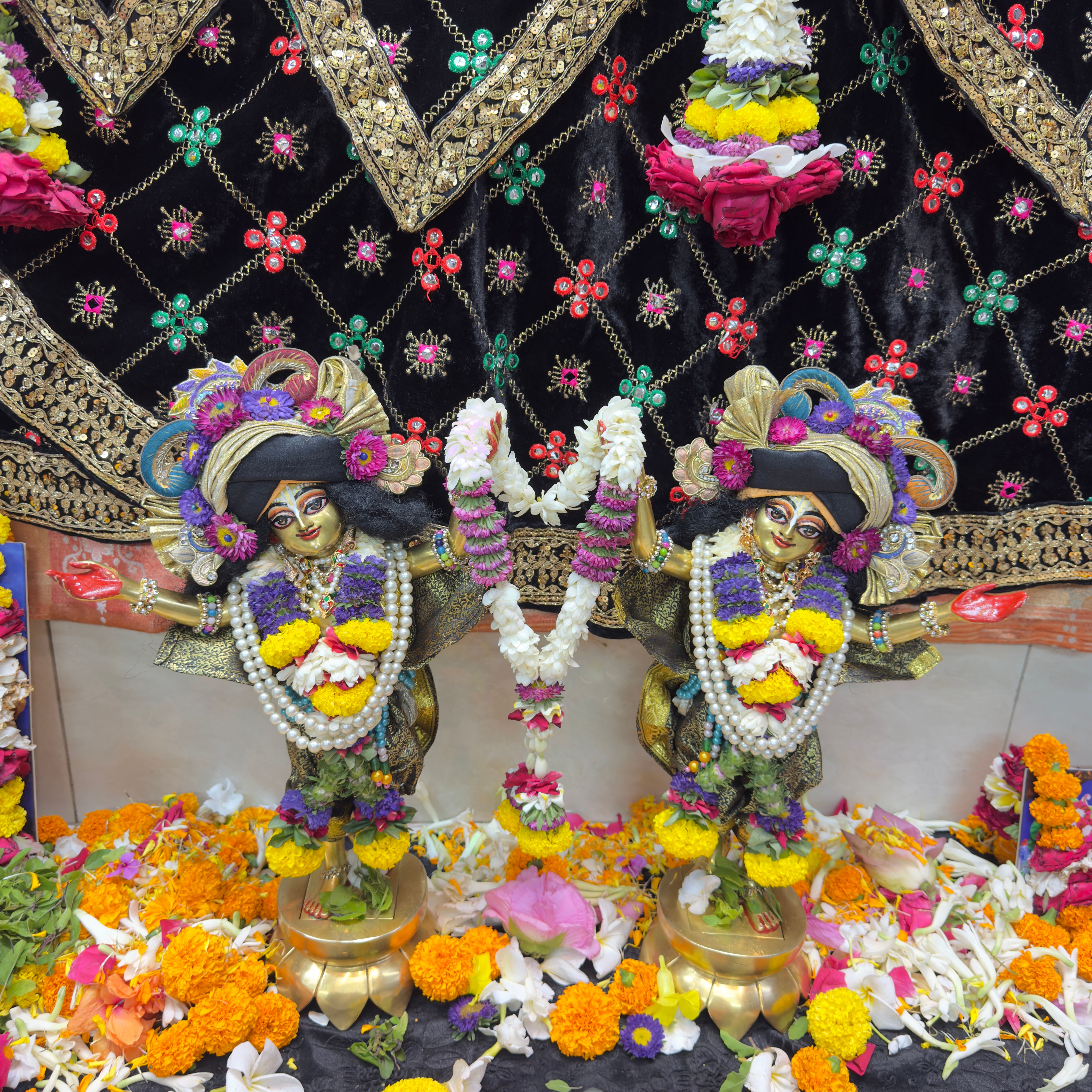 Colorful Indian deity statues adorned with vibrant flower garlands, showcasing a rich cultural tradition.