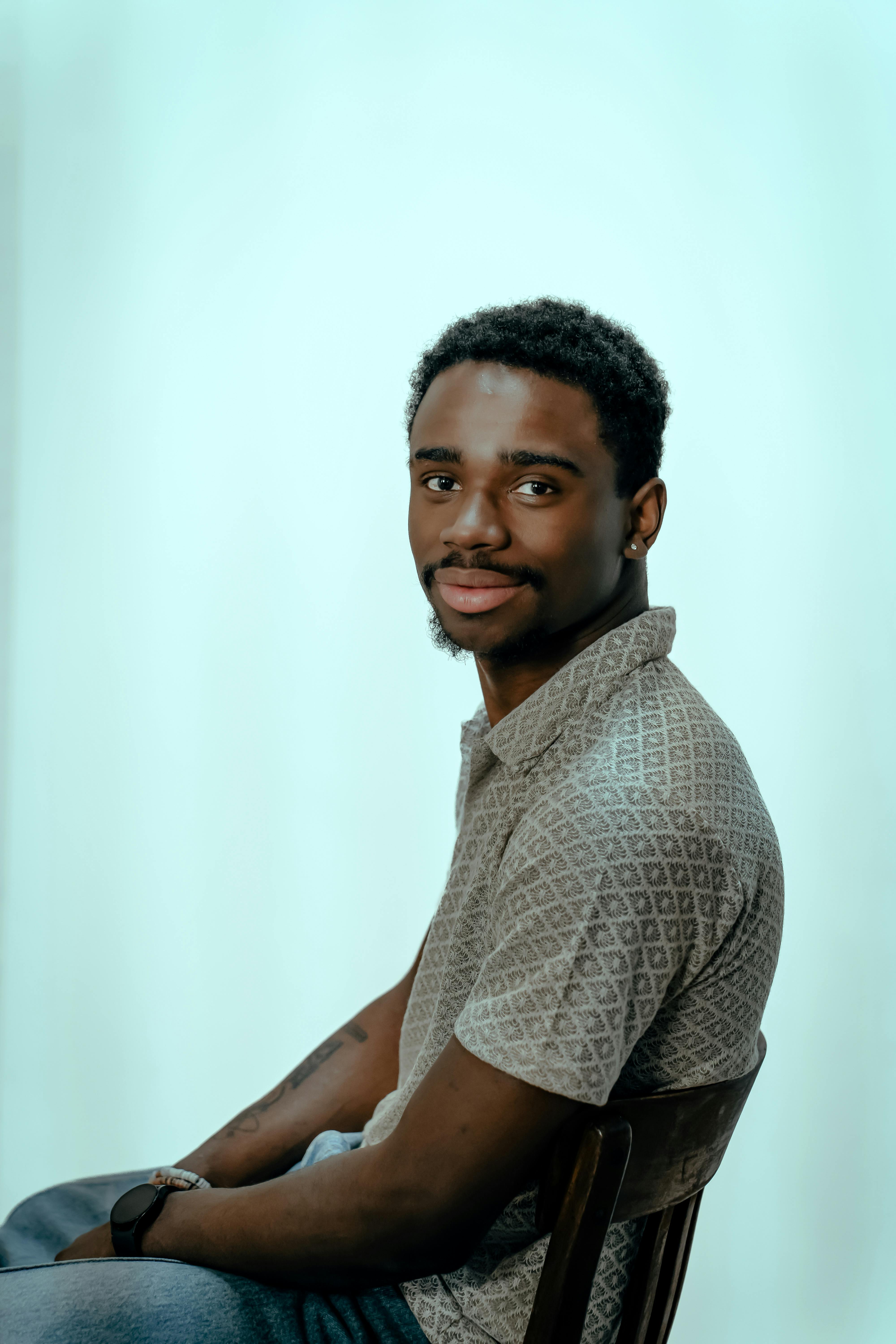 Gratuit Portretul ocazional al unui tânăr adult așezat lateral pe un scaun, cu un zâmbet subtil. Fotografie de stoc