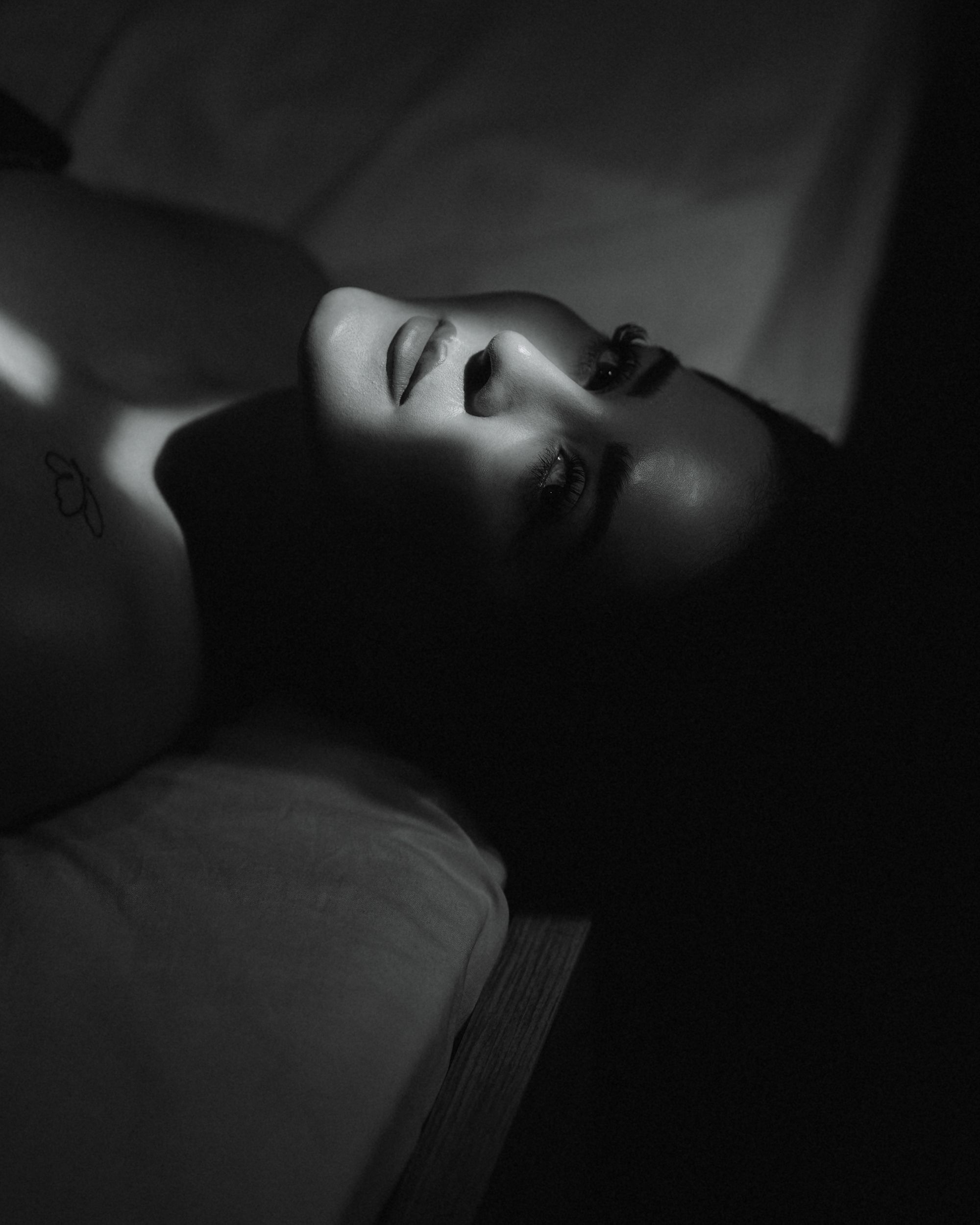 A compelling black and white portrait of a woman with dramatic lighting creating a moody atmosphere.