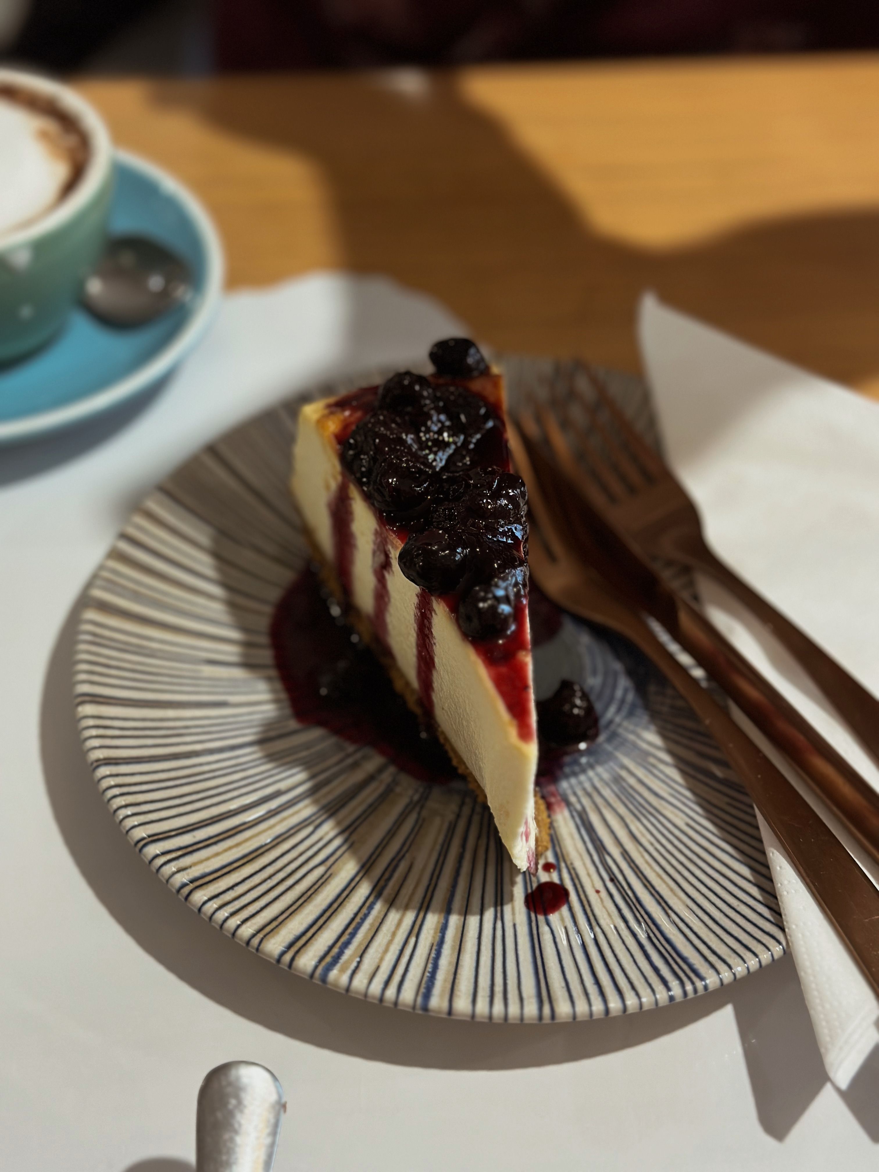 A slice of creamy cheesecake topped with berry compote served on a stylish plate, perfect for dessert lovers.