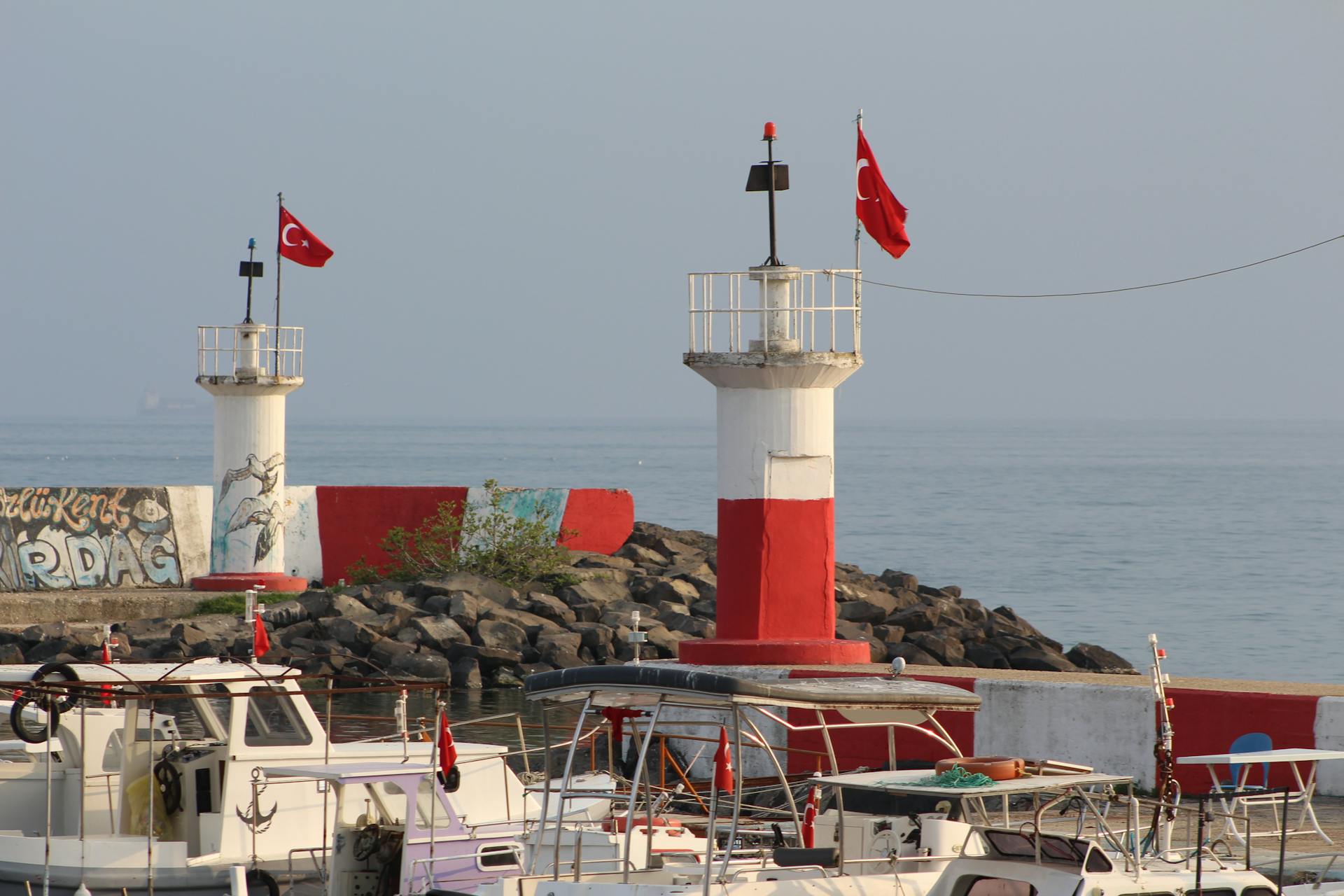 Picturesque view of Tekirdağ harbor with boats and Turkish flag lighthouses.