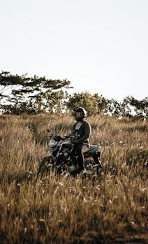 A motorcyclist rides through a grassy field enjoying a peaceful outdoor journey.