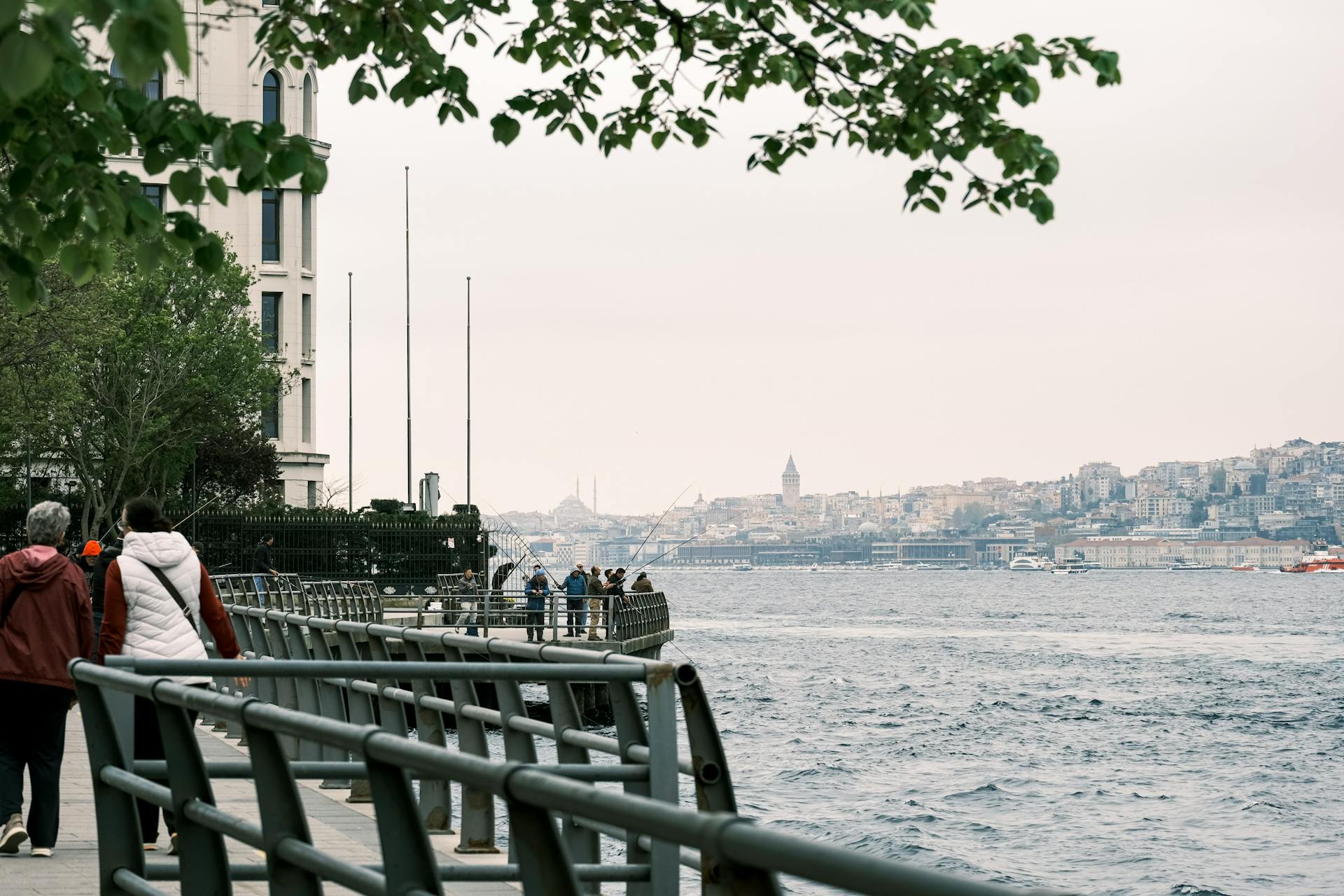 Explore a serene seaside walkway with a view of the iconic city skyline in the distance.